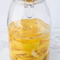 A large drink dispenser with lemon rinds and alcohol to make limoncello