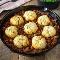 A pan of minced beef and carrots topped with crispy dumplings