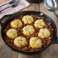 A cast iron skillet with minced beef and dumplings