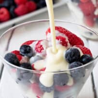 Pouring hot custard over frozen berries.