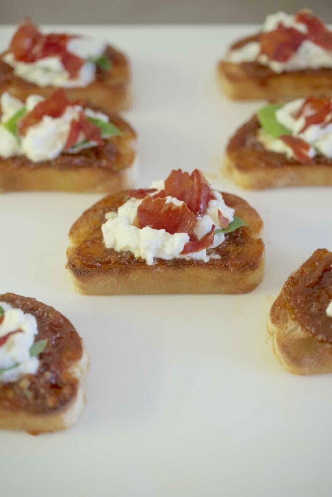 Crostini topped with sun-dried tomato pesto, ricotta and basil