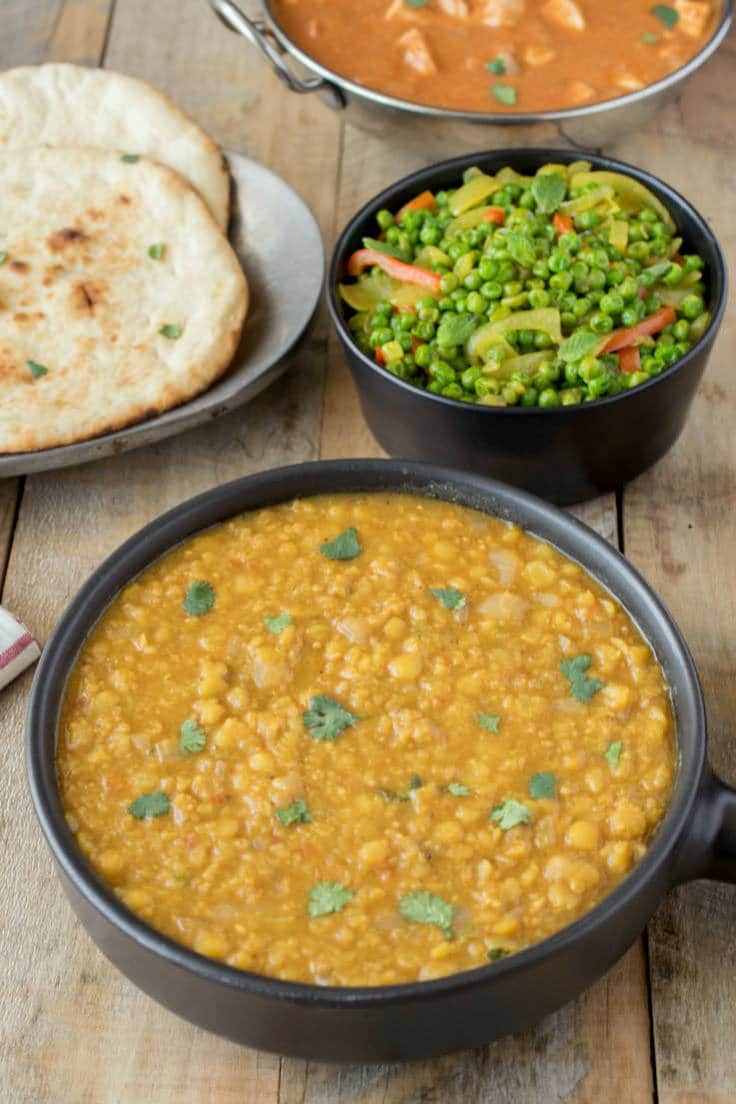 A bowl of Indian dal with naan bread and Indian spiced peas