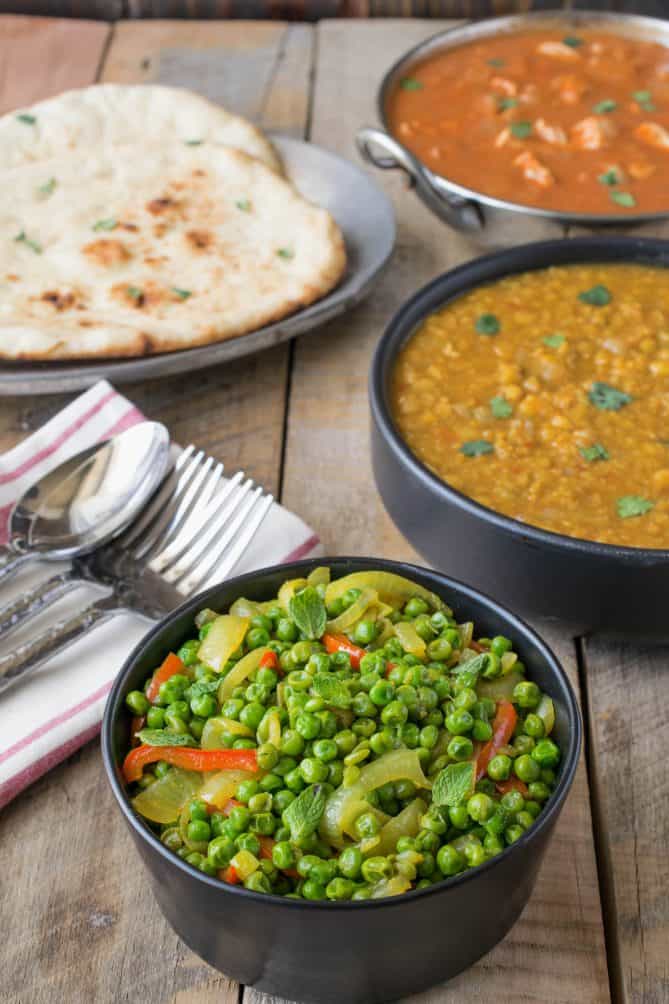 A bowl of peas and vegetables with dal, curry and naan bread