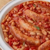Beans and sausage in a casserole with tomato and rosemary