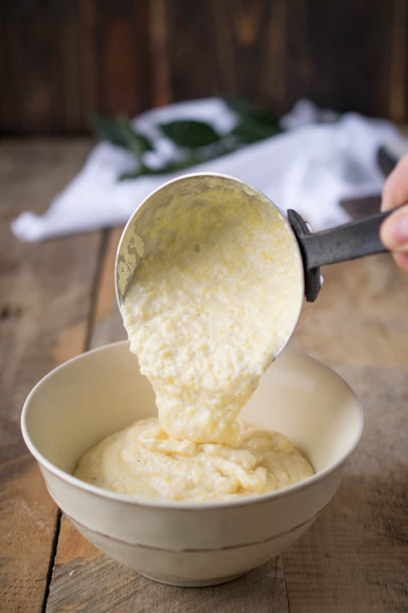Pouring warm polenta into a white bowl
