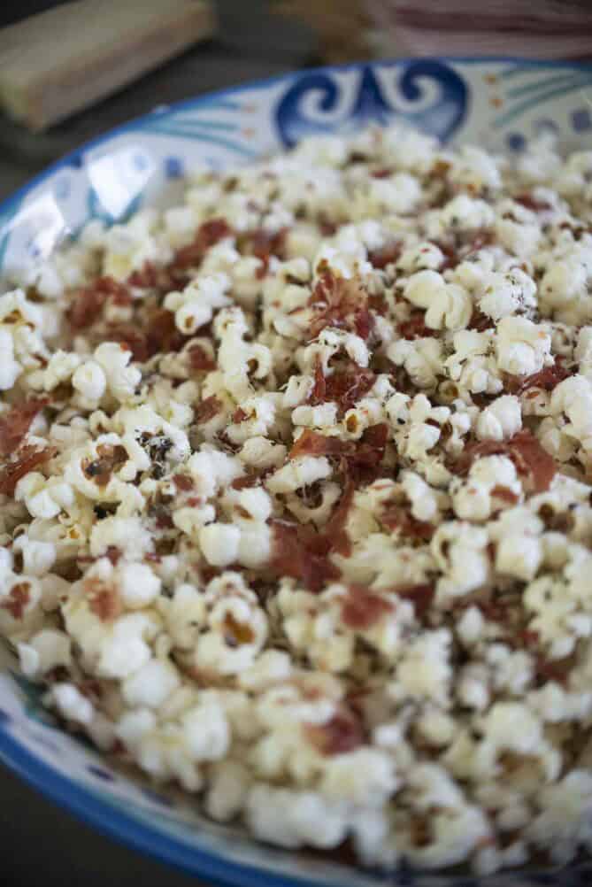 A closeup of popcorn topped with Parmesan cheese and crispy prosciutto