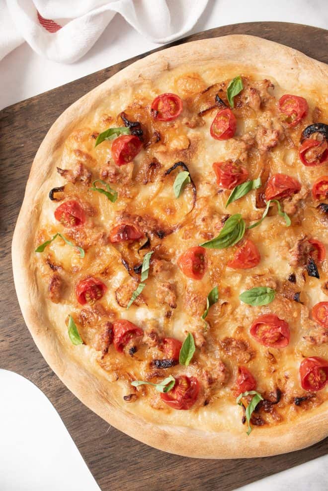 Italian sausage and caramelized onion pizza from overhead on a wood board