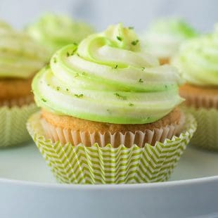 Key lime cupcakes on a cake stand in green and white striped cups