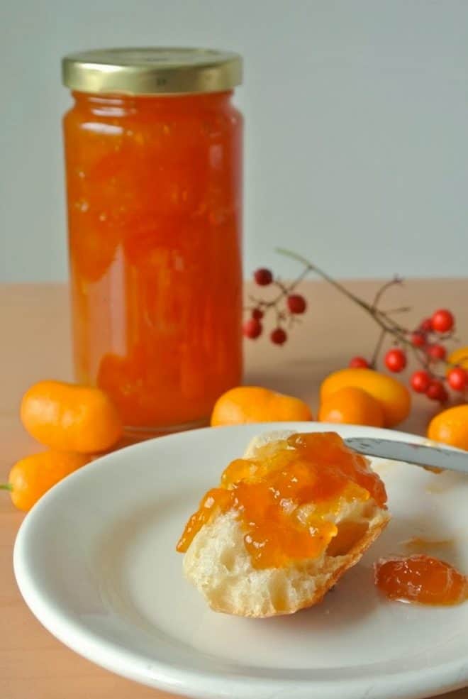 A jar of kumquat marmalade with some spread onto bread