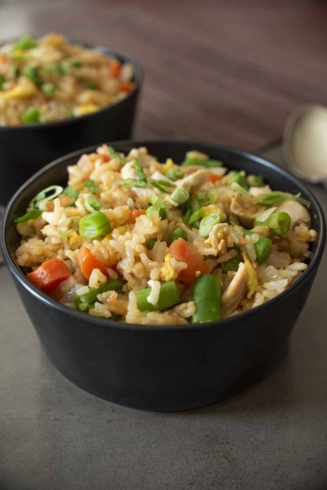 Fried rice using leftover vegetables and chicken in a black bowl