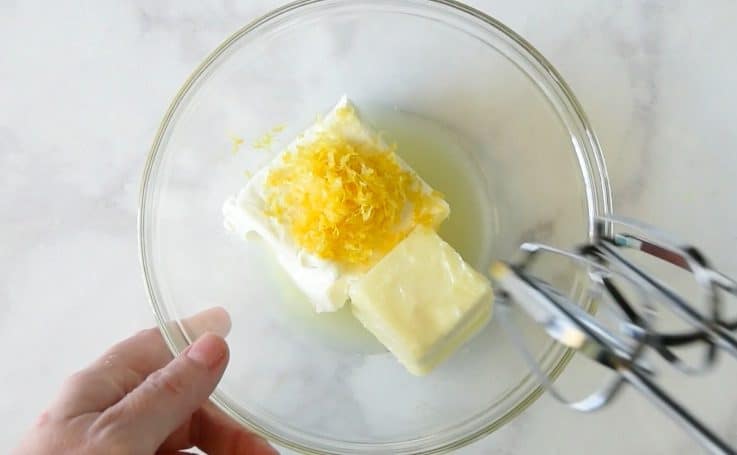 Softened cream cheese, butter and lemon zest being mixed in a glass bowl