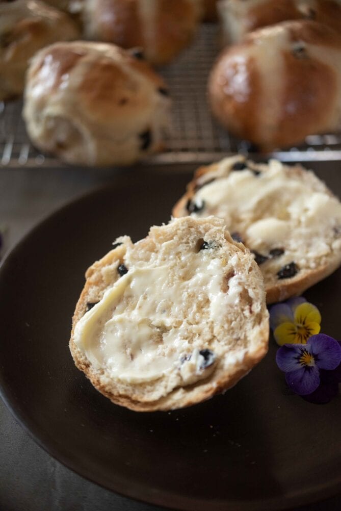 2 halves of a hot cross bun with butter