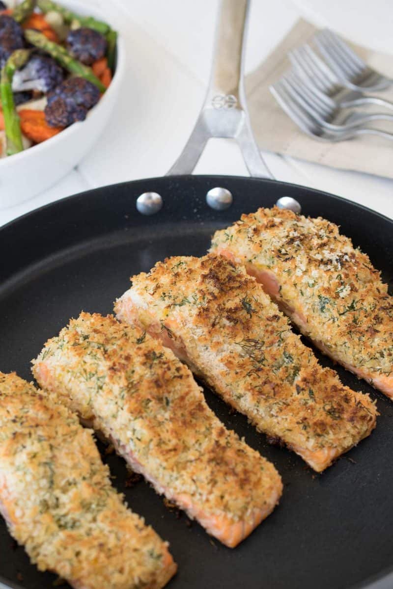 4 Lemon parmesan crusted salmon filets cooking in a large skillet