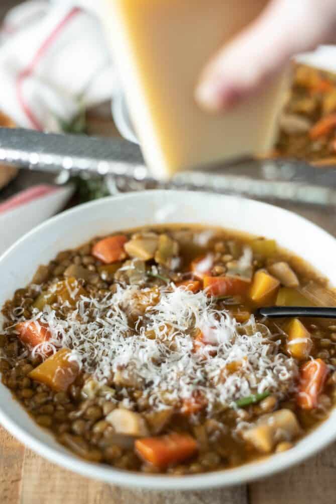 Grating Parmesan cheese into a bowl of soup