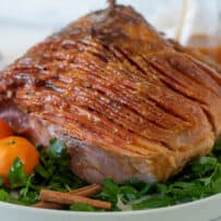 A baked holiday ham on top of parsley garnished with mandarin oranges