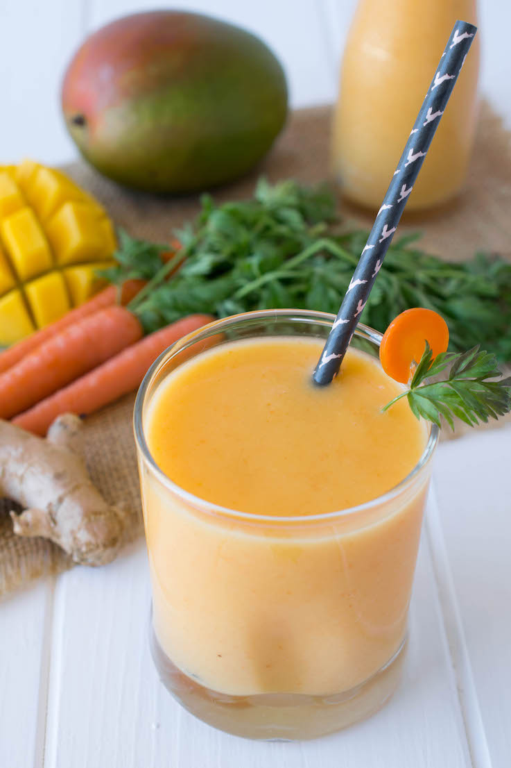 A vibrant orange smoothie in a glass with a straw