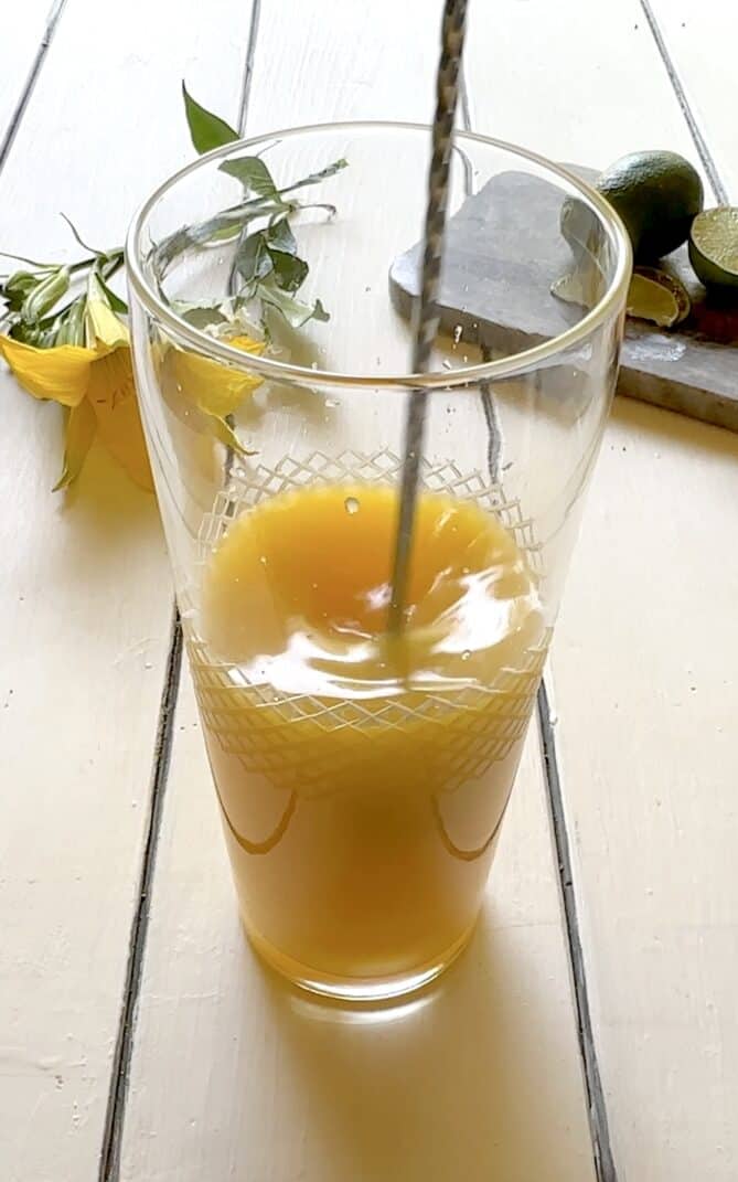 Stirring a large pitcher of mango drink