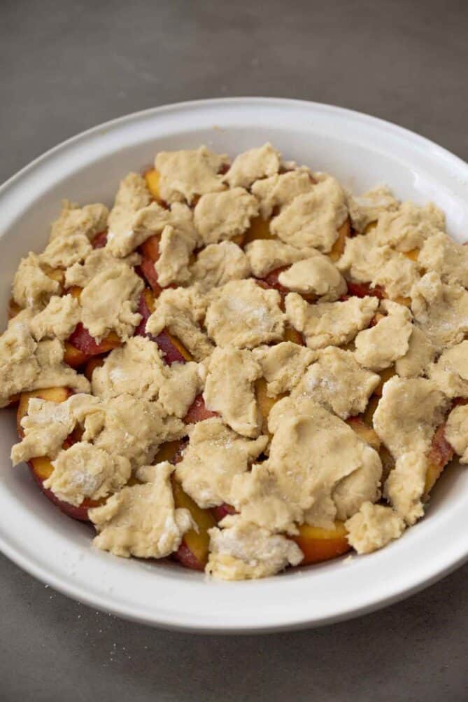 Scone dough on top of peaches sprinkled with sugar