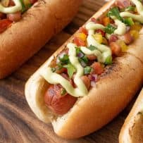 A closeup of the hot dog showing the pinto beans, salsa and avocado crema toppings