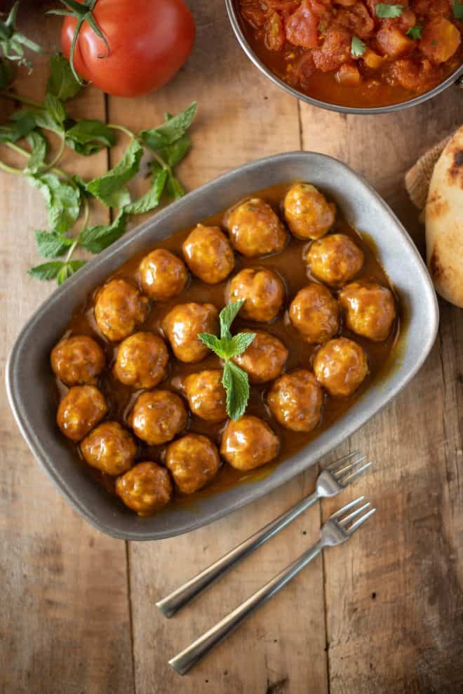 Mini meatballs viewed from overhead on a grey plate with 2 forks