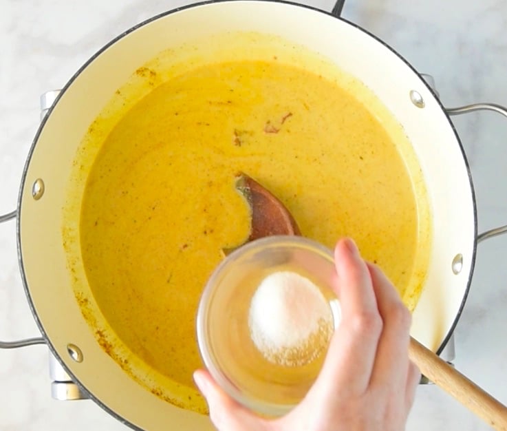 Coconut milk and salt is added to a pan of Indian spices