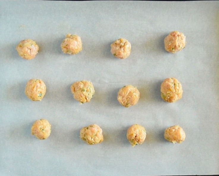 MIni Indian meatballs are lined up on a baking sheet ready to be baked