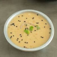 A grey bowl of miso dressing sauce and marinade topped with micro greens and sesame seeds
