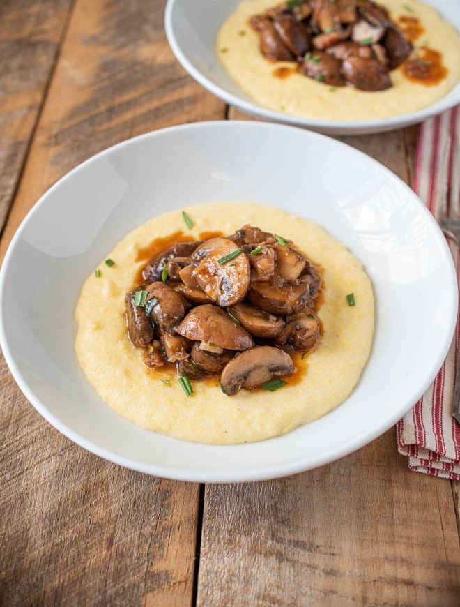 A white bowl of mushroom pancetta ragu served over polenta