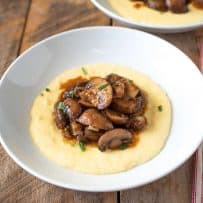 Creamy polenta is served topped with meaty mushroom pancetta ragu