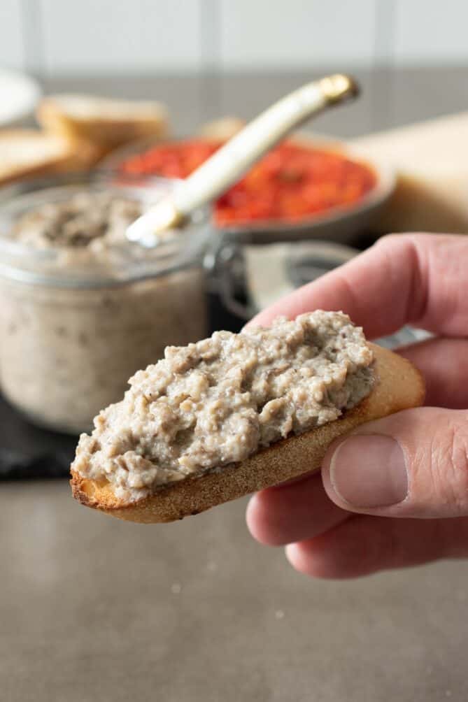 Holding a crostini topped with mushroom pâté