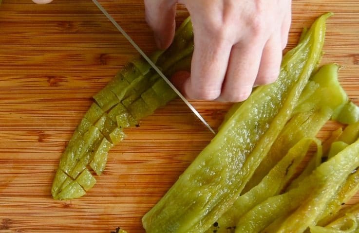Green chiles being chopped on a cutting board