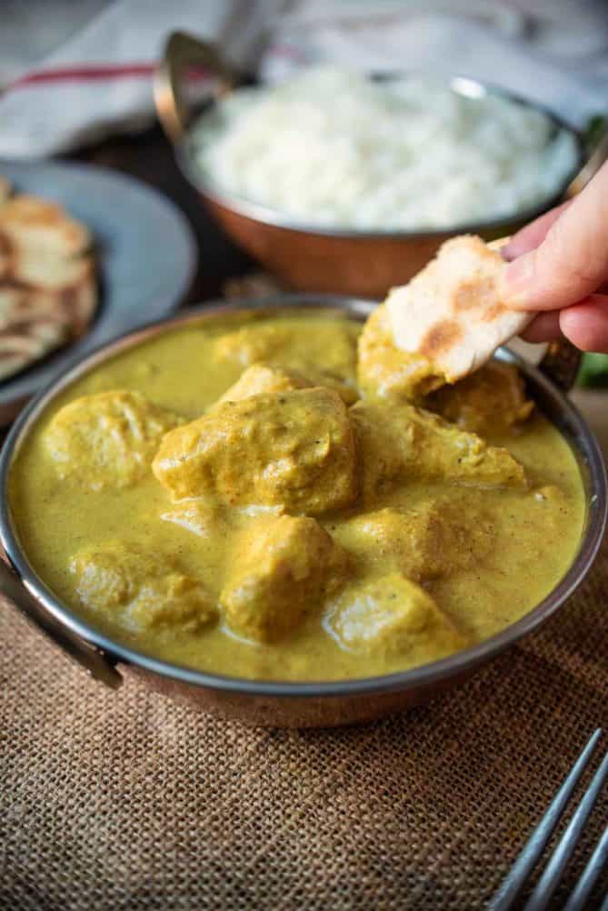 Dipping a piece of naan bread in a curry