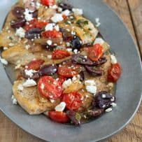 A closeup showing the chicken topped with tomatoes, olives and feta cheese