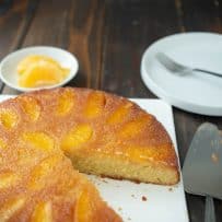 A whole orange salted caramel upside down cake on a square plate with a slice cut out