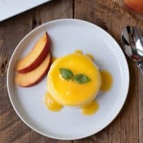 Panna cotta with peach sauce, peach slices and basil leaves