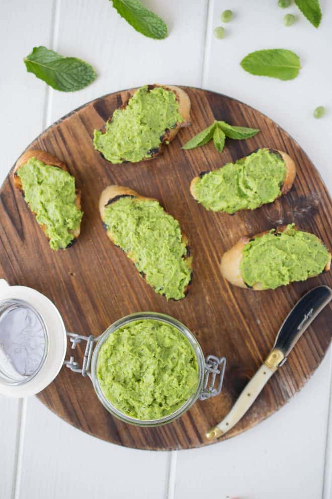The pesto viewed from overhead on a round board with a knife and fresh mint leaves