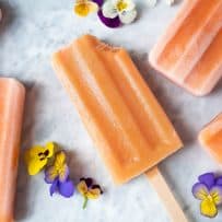 A peach frozen yogurt popsicle with a bite taken from the top right