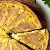 A closeup of pear and goat cheese quiche with a piece sliced
