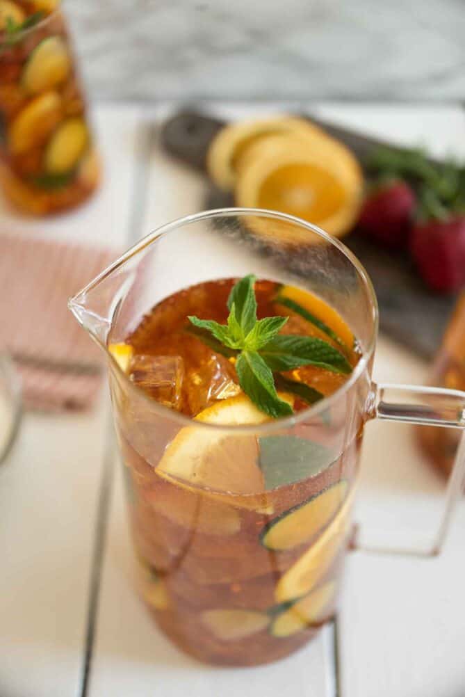 A fruity drink in a pitcher garnished with fresh mint on top