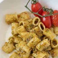 Rigatoni pasta coated in pistachio pesto with cherry tomatoes