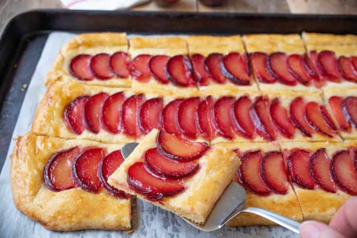 Lifting a slice of plum tart with a cake slicer