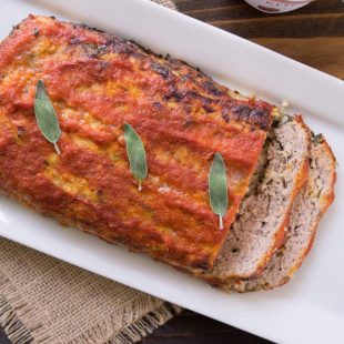 A whole pork apple and sage meatloaf on a long white platter