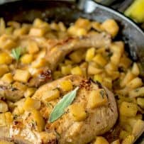 A closeup of a pork chop with chopped apples and sage