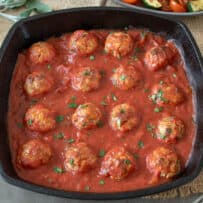 A pan of pork meatballs in a marinara sauce