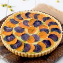 Potato and vegetable quiche topped with slices of orange and purple potatoes