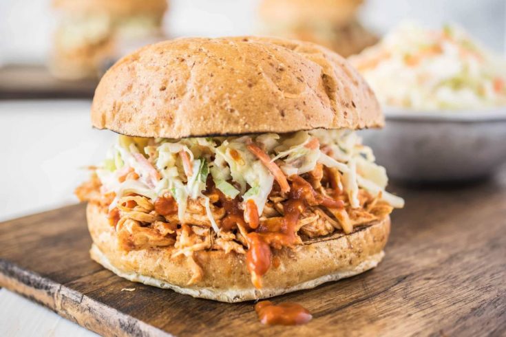A side view of pulled chicken piled onto a bun and topped with coleslaw