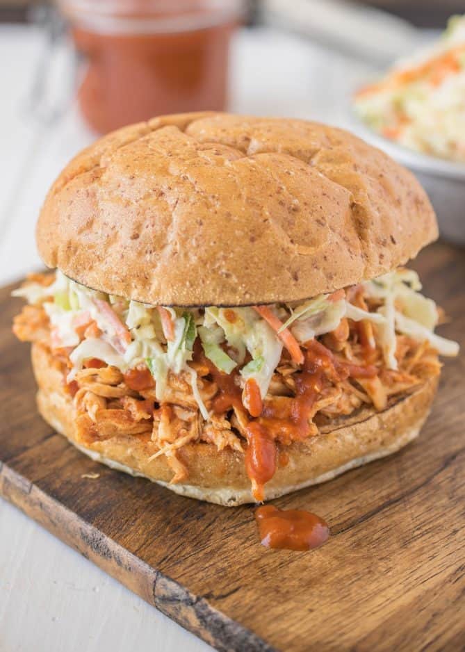 A closeup showing the barbecue sauce dripping out of the sandwich onto the board
