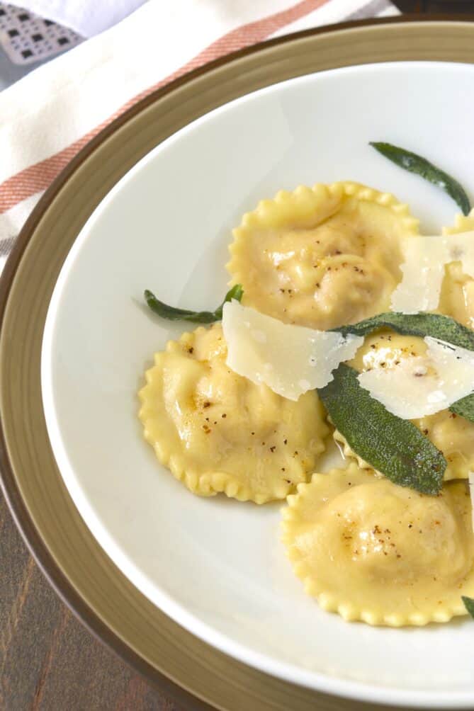 Round ravioli with fluted edges topped with browned butter, crispy sage leaves and shave Parmesan
