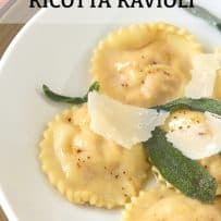 Fluted edge round ravioli on a white plate with crispy sage leaves and shaved Parmesan cheese