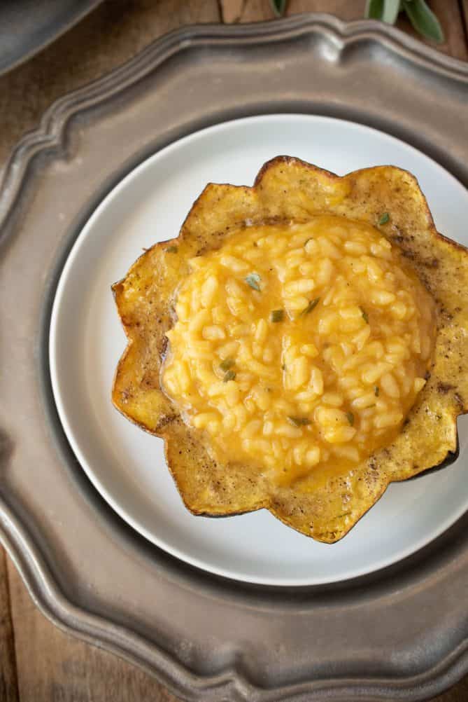 Vibrant orange pumpkin risotto sitting inside a roasted acorn squash